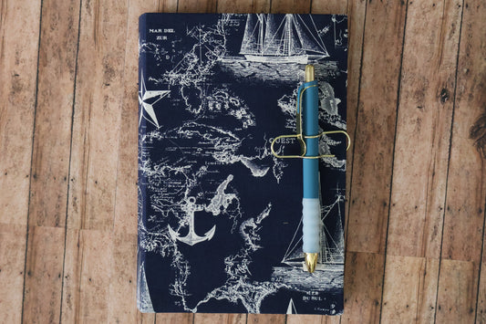 Nautical-themed notebook with a pen on a wooden surface