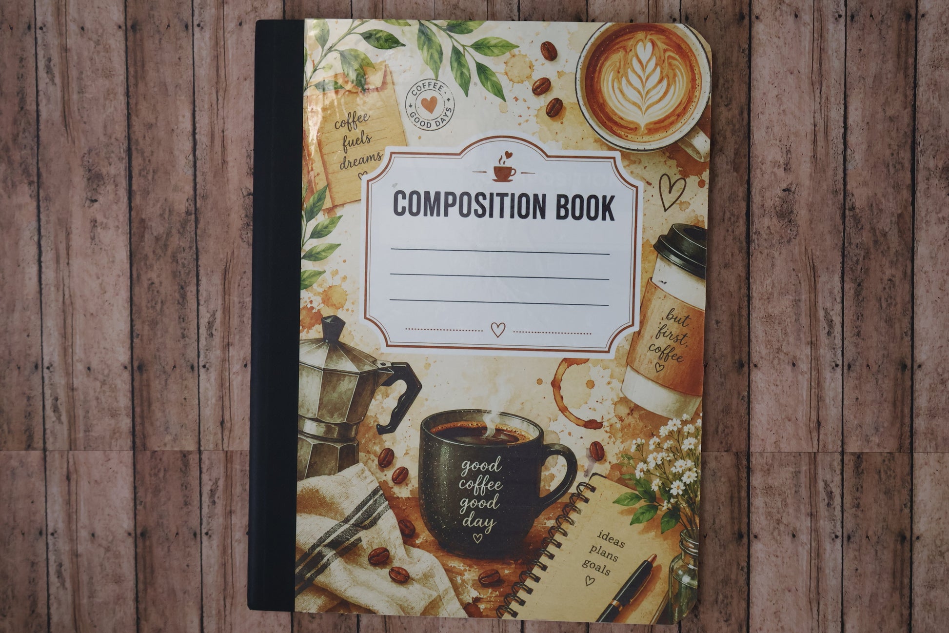 Composition book with coffee-themed cover on a wooden surface