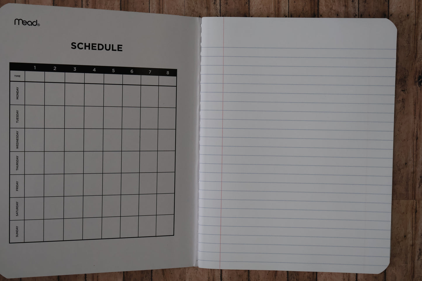 Open notebook with lined pages and a grid schedule on a wooden surface