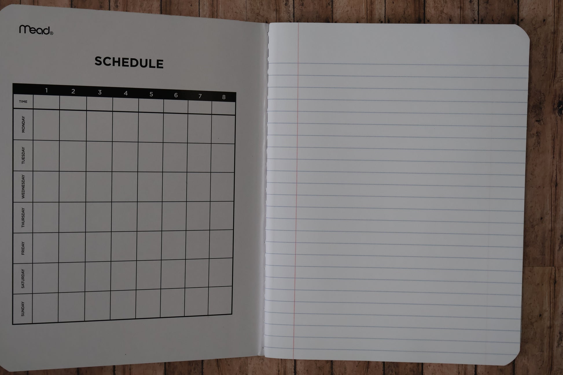 Open notebook with lined pages and a grid schedule on a wooden surface